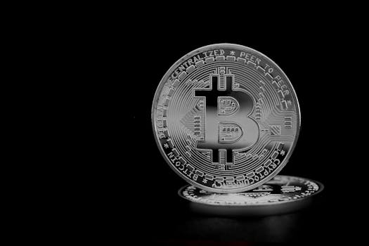 Close-up of a silver bitcoin coin, highlighting the cryptocurrency symbol on a black background.