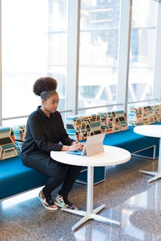 Confident woman working on her laptop in a bright and modern office lounge area.