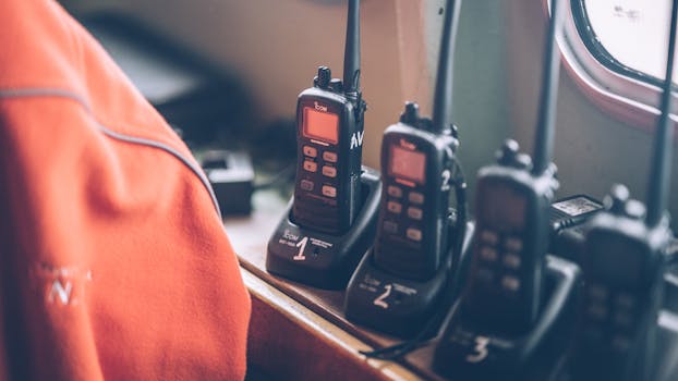 Four wireless walkie talkies in charging stations on a wooden dock indoors.